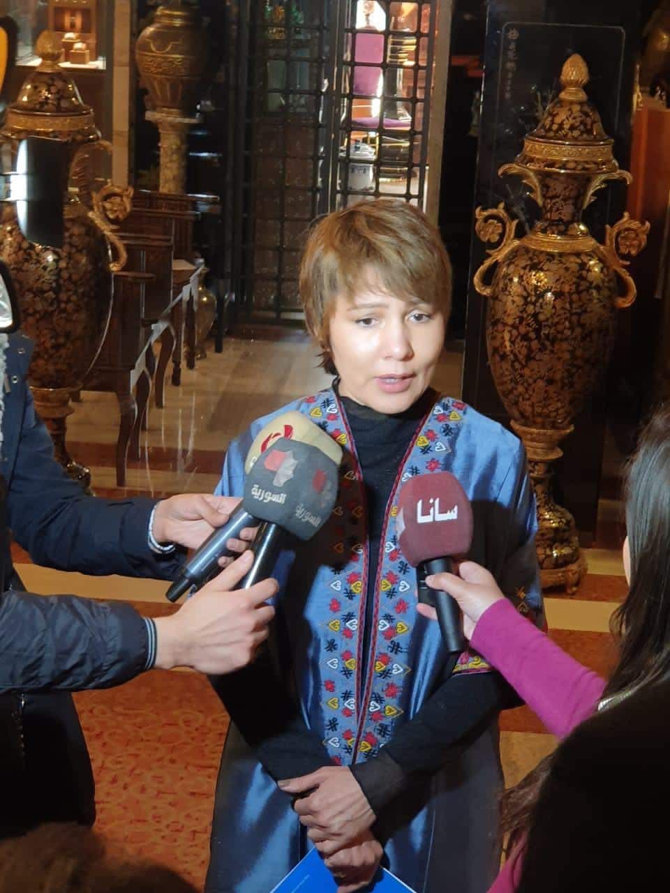 Dr Akjemal Magtymova answering journalists’ questions, microphones held towards her
