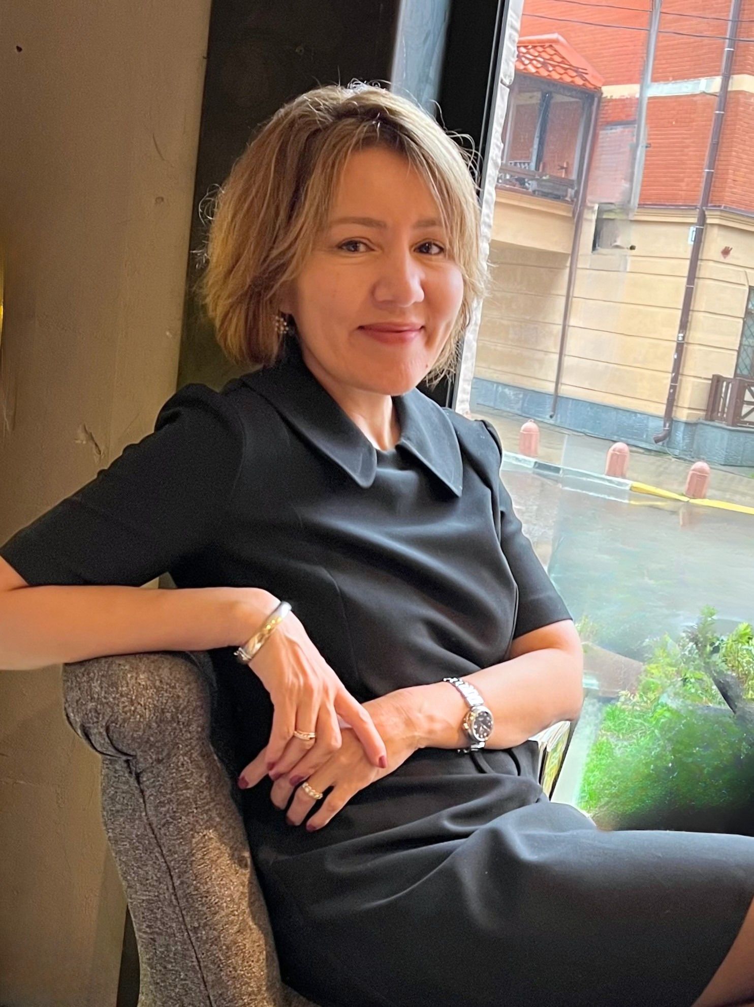 Dr Akjemal Magtymova by a glass wall, listening, with a city skyline behind her